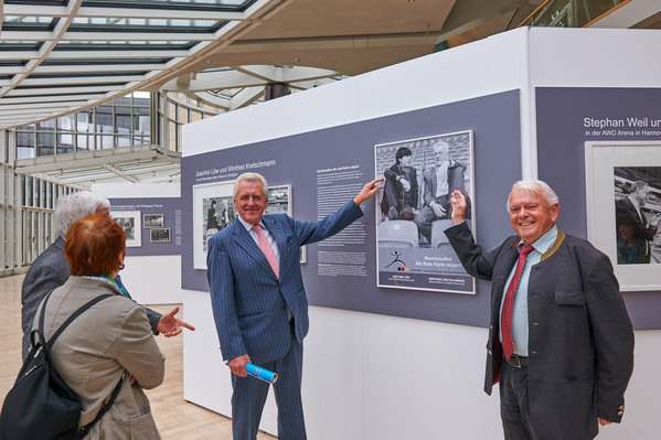 Besucher der Wanderausstellung betrachten Plakat von Joachim Löw und Winfried Kretschmann